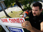 Renzo Salazar, from Real Signs of Ace Post Holding Inc., placed a bank owned sign on top of a for sale sign outside a foreclosed home in Miami last month. Renzo Salazar, from Real Signs of Ace Post Holding Inc., placed a bank owned sign on top of a for sale sign outside a foreclosed home in Miami last month.
