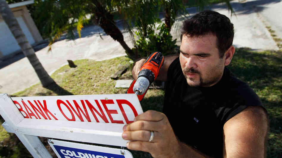 Renzo Salazar, from Real Signs of Ace Post Holding Inc., placed a bank owned sign on top of a for sale sign outside a foreclosed home in Miami last month.
