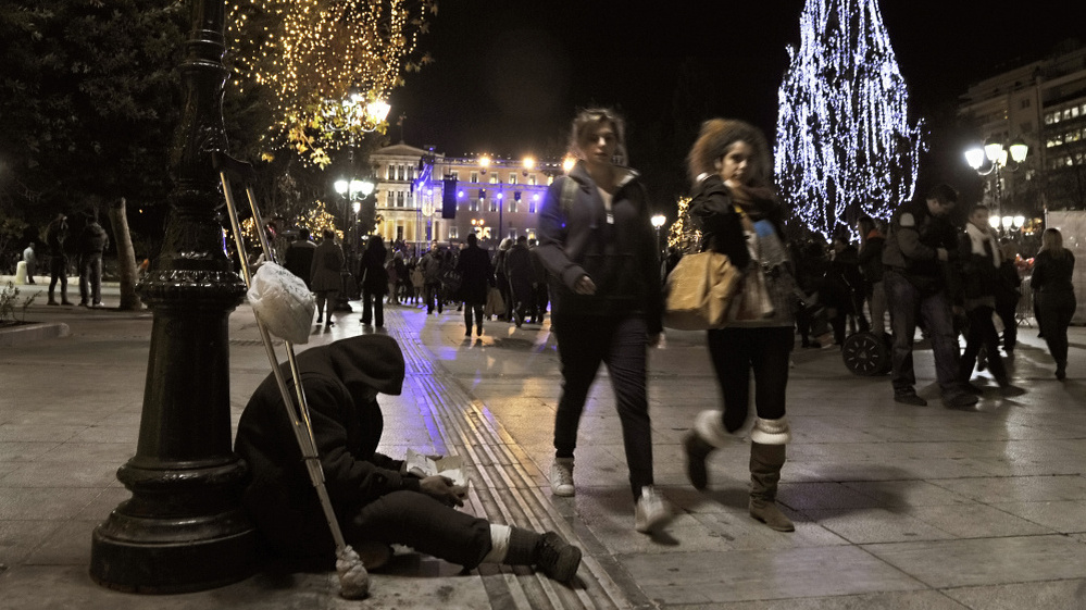 A homeless man begs for money during the launch of Christmas celebrations in Athens' central Syntagma Square, Dec. 9. Difficult economic times have meant subdued holiday activities — and even carolers, who traditionally receive money for their songs, are feeling the pinch.