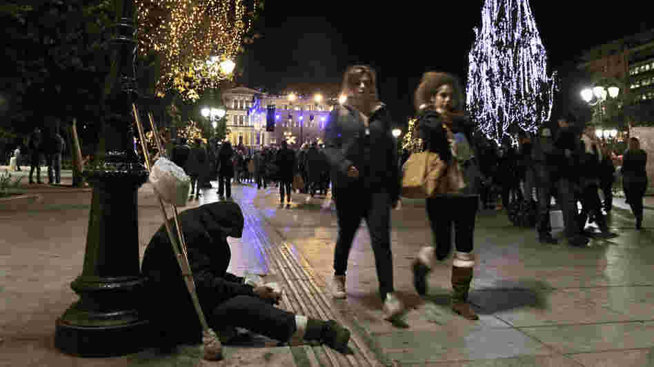 A homeless man begs for money during the launch of Christmas celebrations in Athens' central Syntagma Square, Dec. 9. Difficult economic times have meant subdued holiday activities — and even carolers, who traditionally receive money for their songs, are feeling the pinch.