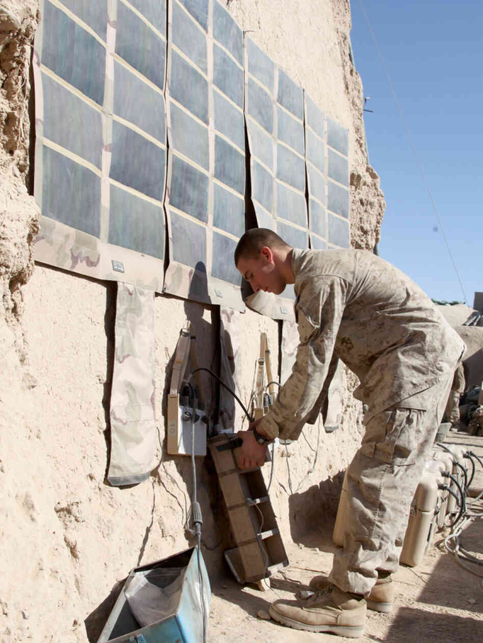 In this photo released by the U.S. Marines and taken in December 2010, Lance Cpl. Dakota Hicks, from Laharpe, Ill., connects a radio battery to a portable solar panel communication system in Sangin District, in Afghanistan.The U.S. military is trying to wean itself off reliance on fossil fuels by employing solar energy and biofuels, among other measures.