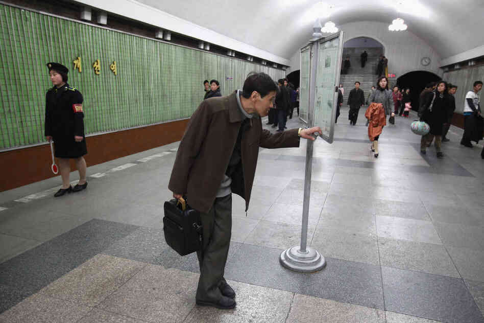 A man reads an official state newspaper on the platform of the Yongwang subway station.