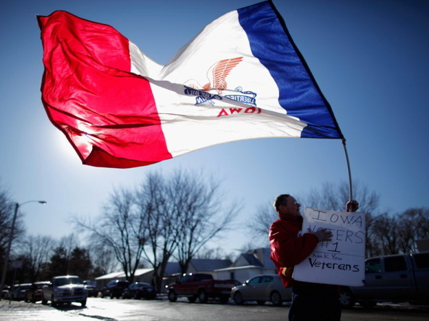 Edward Lewis of Council Bluffs waved an Iowa state flag outside the Family Table Restaurant in Atlantic on Sunday, before the arrival of former Massachusetts governor and Republican presidential candidate Mitt Romney.