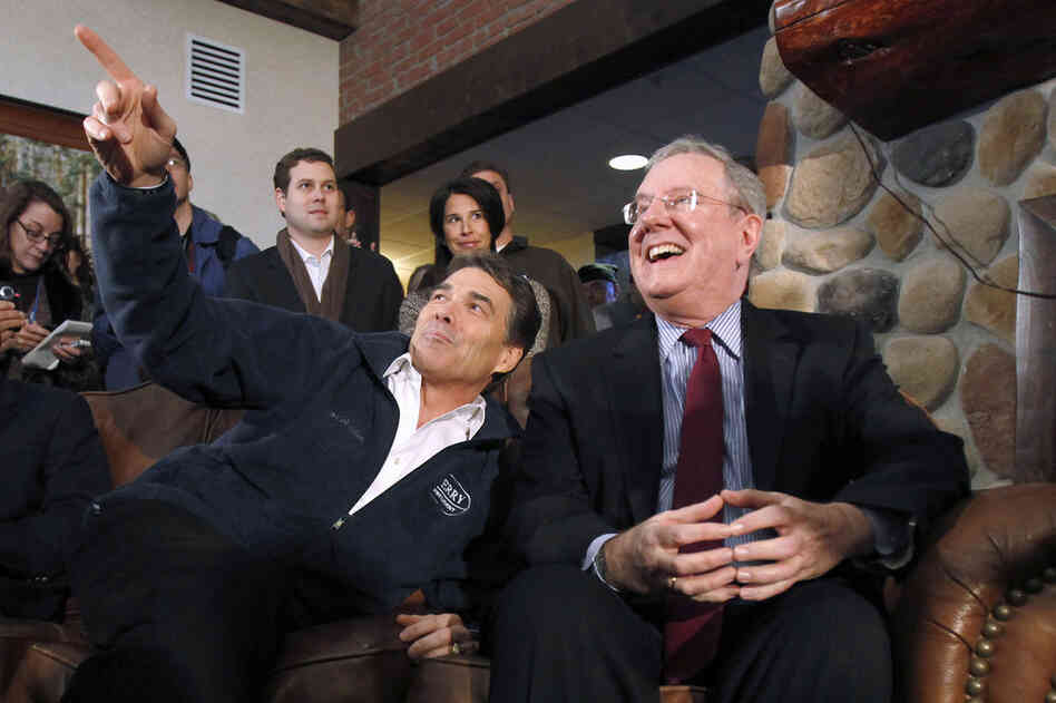 Texas Gov. Rick Perry sits with 1996 and 2000 presidential candidate Steve Forbes, right, during a campaign stop at the Stoney Creek Inn Monday in Sioux City, Iowa. 