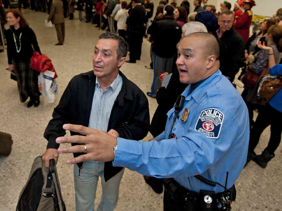 A police officer directs travelers arriving at Dulles International Airport. Some think the passenger experience hasn't been very good overall, and is unlikely to improve in the new year.