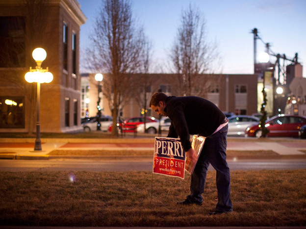 A supporter of Texas governor Rick Perry places campaign signs outside the Hotel Pattee before an event on Monday in Perry, Iowa. 