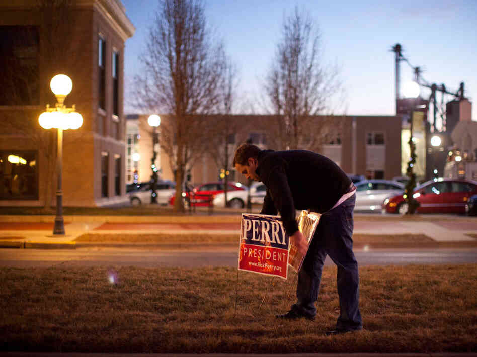 A supporter of Texas governor Rick Perry places campaign signs outside the Hotel Pattee before an event on Monday in Perry, Iowa. 