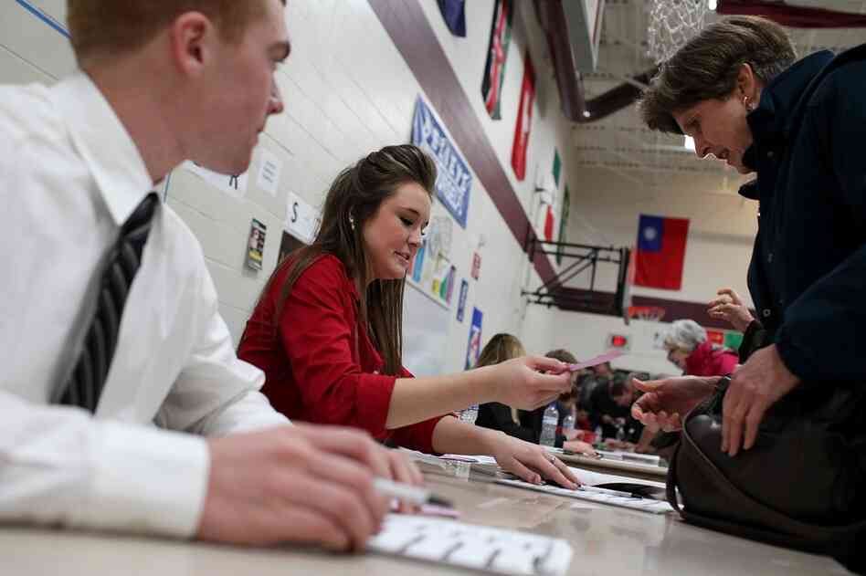 Kate Paul (center) registers a caucusgoer at the Ankeny 9 Republican caucus in Ankeny. 