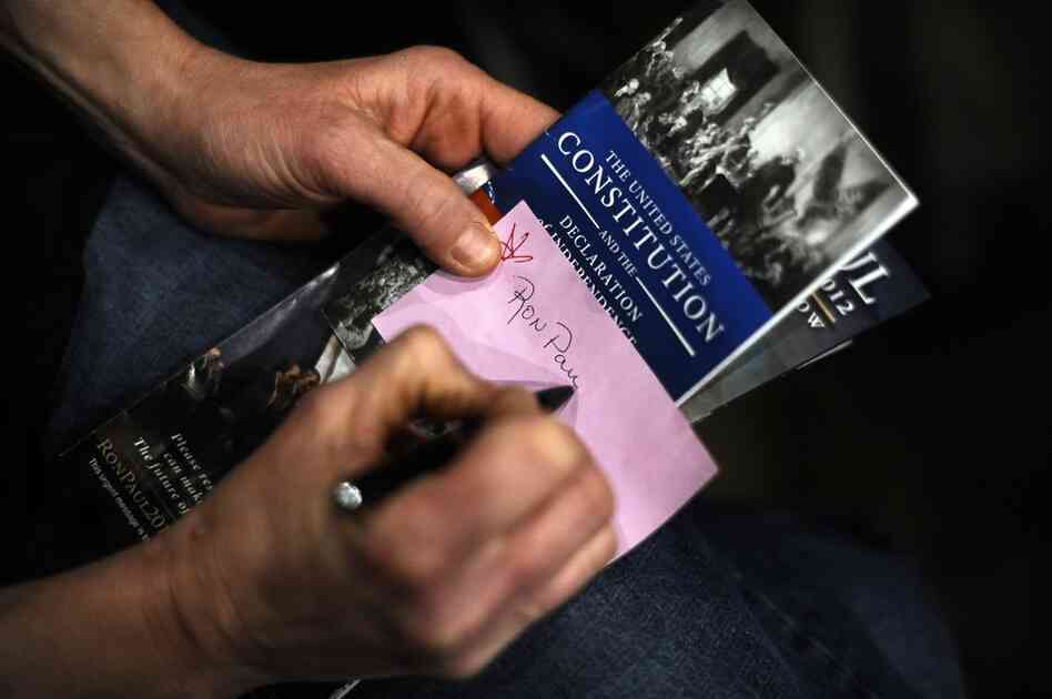 A caucusgoer writes his vote on a ballot in Des Moines. 