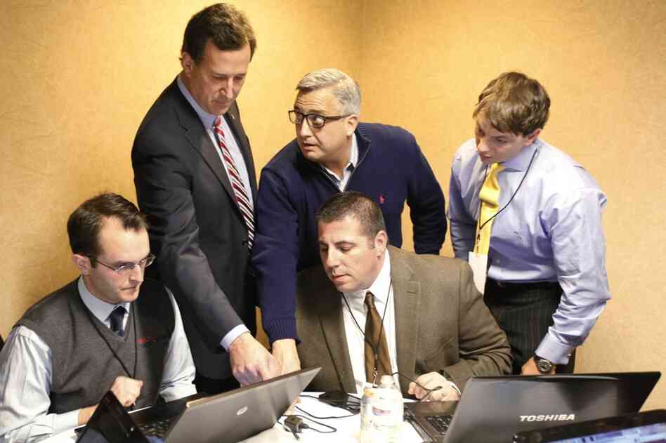 Rick Santorum (second from left) looks over caucus returns with campaign staff in his hotel room in Johnston. 