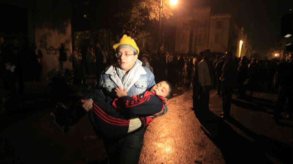 A demonstrator in Cairo runs with an injured child during clashes with security forces last month. A growing number of children are participating in anti-government protests, and their numbers are rising among the casualties.