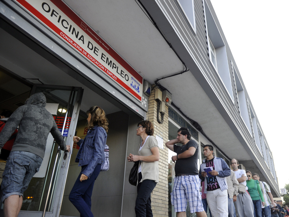 People wait in line at a government employment office in Madrid.