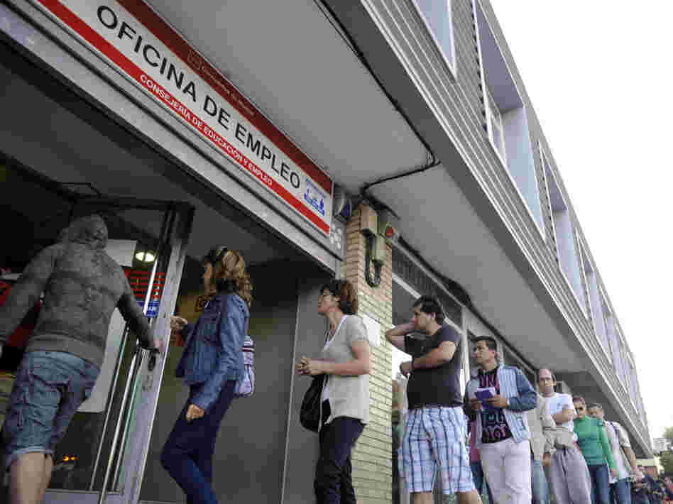 People wait in line at a government employment office in Madrid.