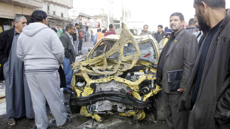 Iraqi men examine some of the wreckage left behind after one of today's explosions in Baghdad.