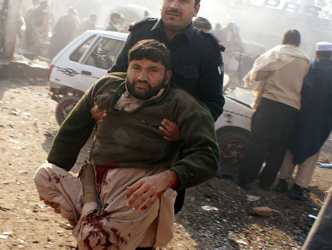 A member of the security personnel carries an injured person to a vehicle after an explosion in Pakistani tribal area of Khyber near Peshawar, Pakistan on Tuesday.