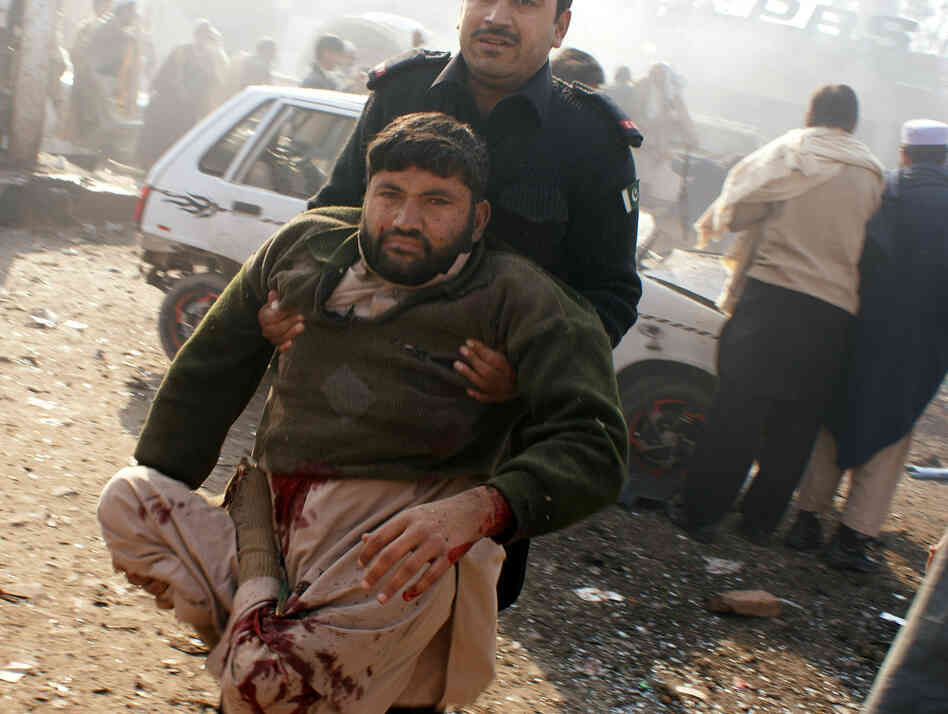A member of the security personnel carries an injured person to a vehicle after an explosion in Pakistani tribal area of Khyber near Peshawar, Pakistan on Tuesday.