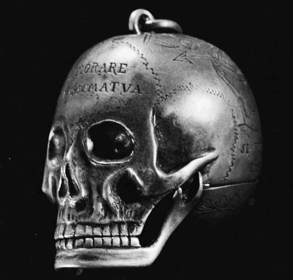 An engraved metal skull which once belonged to Mary, Queen of Scots, bearing inscriptions relating to death. The skull unhinges to expose a watch.