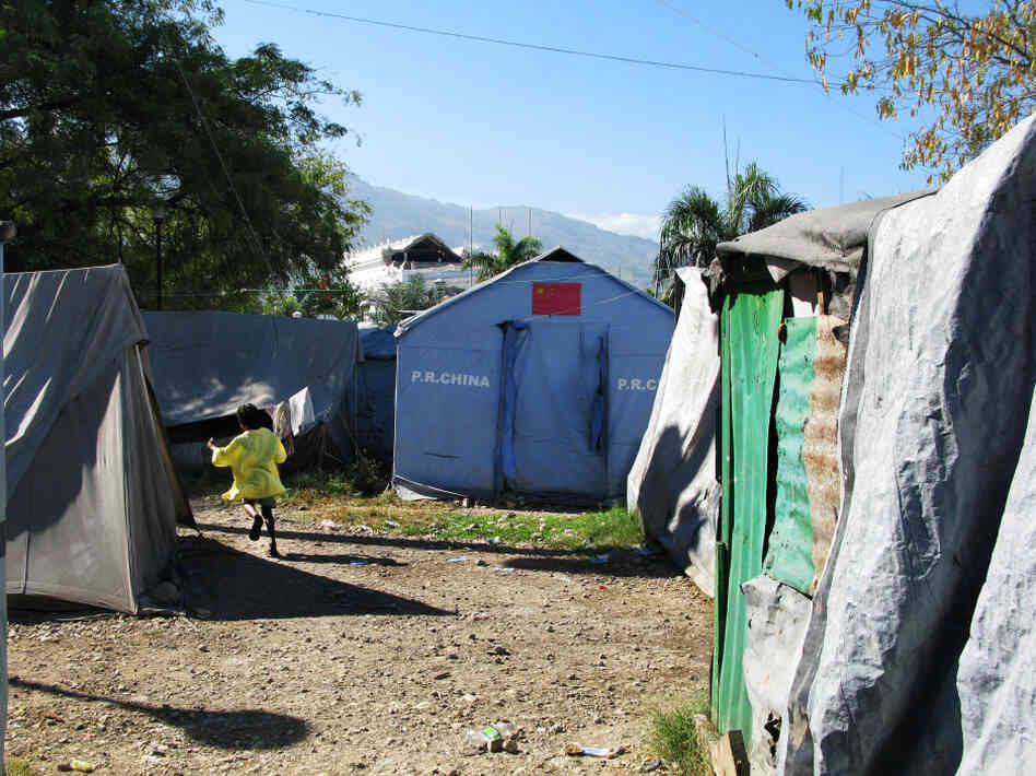 At the Place Pigeon camp, residents bathe in the streets by pouring water over themselves from a basin. 