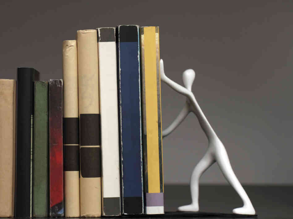 A bookend shaped like a person, holding up a row of books