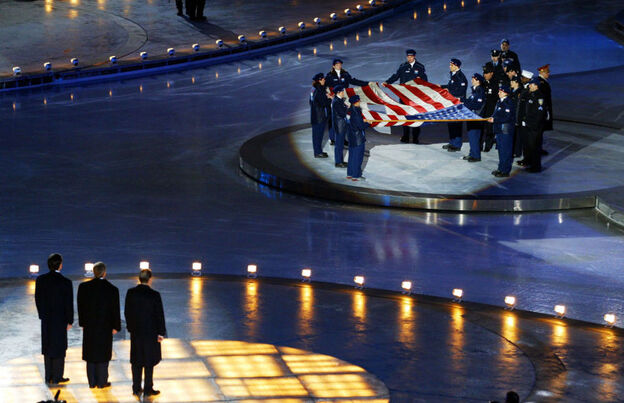  At the opening ceremony of the 2002 Winter Olympics in Salt Lake City, Mitt Romney (left) stands with President George W. Bush (center) and International Olympic Committee President Jacques Rogge (right) in front of the American flag that flew at the World Trade Center before the Sept. 11 terrorist attacks. 