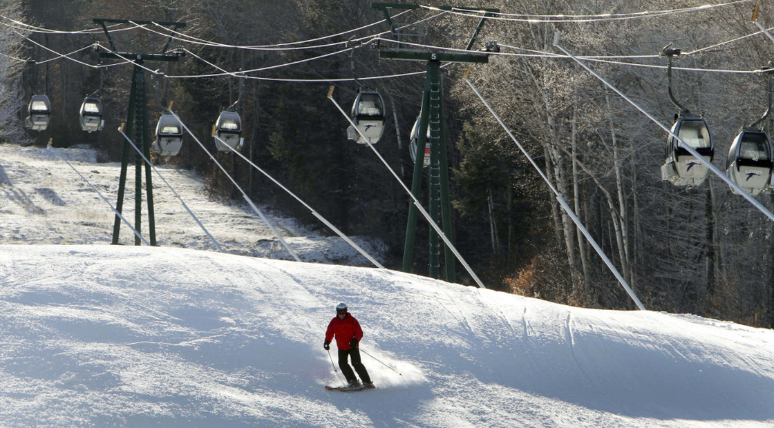 Empty gondolas sit parked above a lone skier in mid-December on an open trail at Loon Mountain ski area in Lincoln, N.H. Warm temperatures have continued to hover above optimal snowmaking levels, making for a late start to the ski season in the Northeast. 