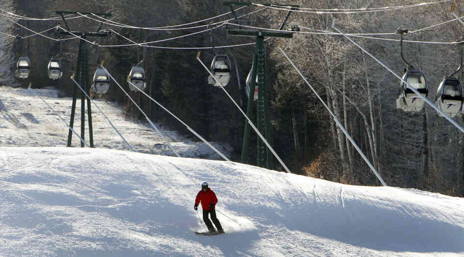 Empty gondolas sit parked above a lone skier in mid-December on an open trail at Loon Mountain ski area in Lincoln, N.H. Warm temperatures have continued to hover above optimal snowmaking levels, making for a late start to the ski season in the Northeast. 