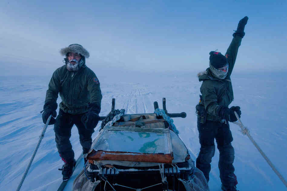 Rotating their arms to stay warm, Jesper Olsen (right) and Rasmus Jergensen ski beside a sled full of supplies: rifles, a radio, first aid, a tent, sleeping bags, a big map, and plenty of dog food.