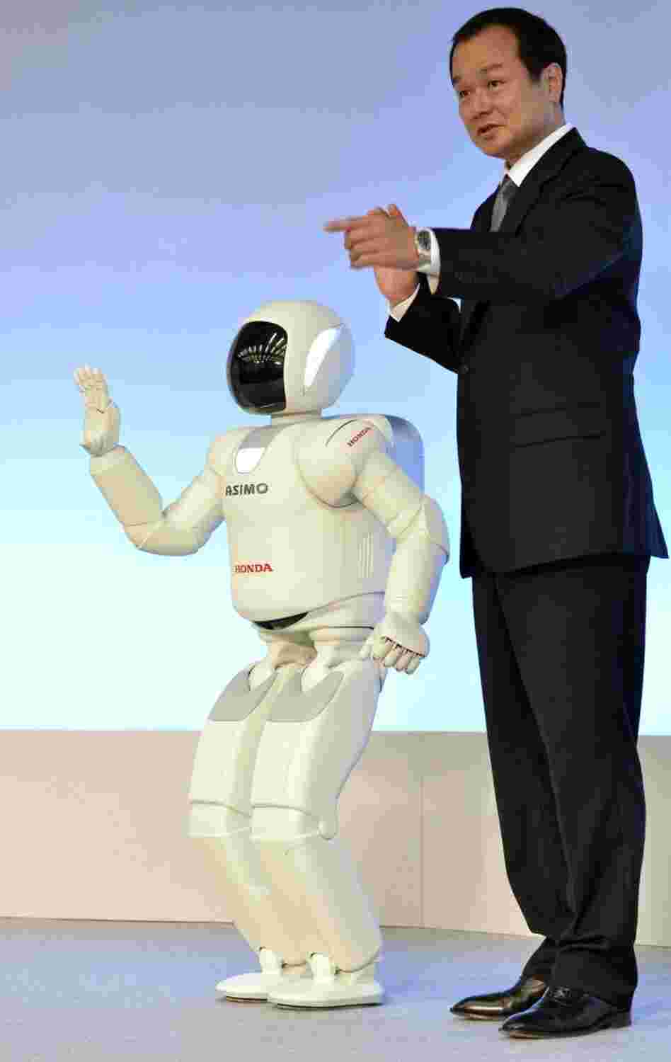 Man and machine stand side-by-side: Honda's Asimo robot. Man and machine stand side-by-side: Honda's Asimo robot.
