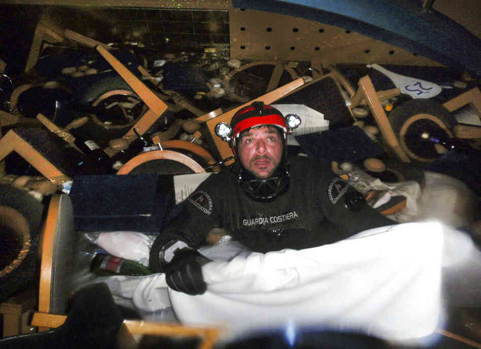 A scuba diver makes his way through floating pieces of furniture while searching for people inside the cruise ship. 