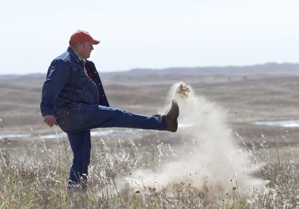 Atkinson, Neb., rancher Bruce Boettcher, who opposes the Keystone XL pipeline, kicks up sand on his land, to demonstrate the fragility of the sandhills near the planned route of the pipeline.