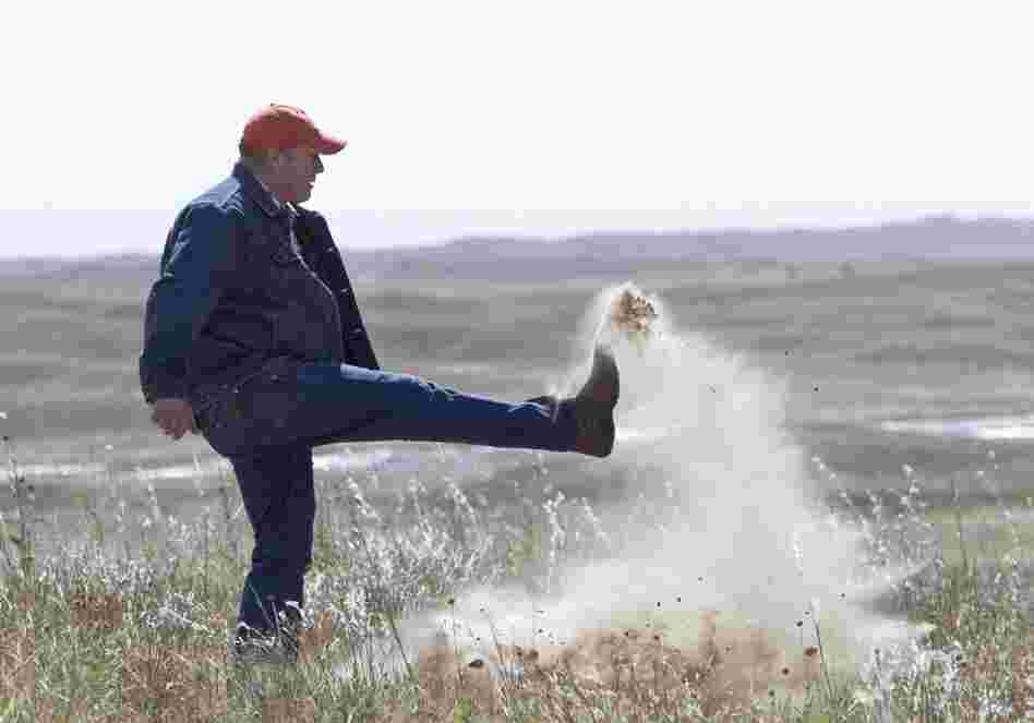 Atkinson, Neb., rancher Bruce Boettcher, who opposes the Keystone XL pipeline, kicks up sand on his land, to demonstrate the fragility of the sandhills near the planned route of the pipeline.