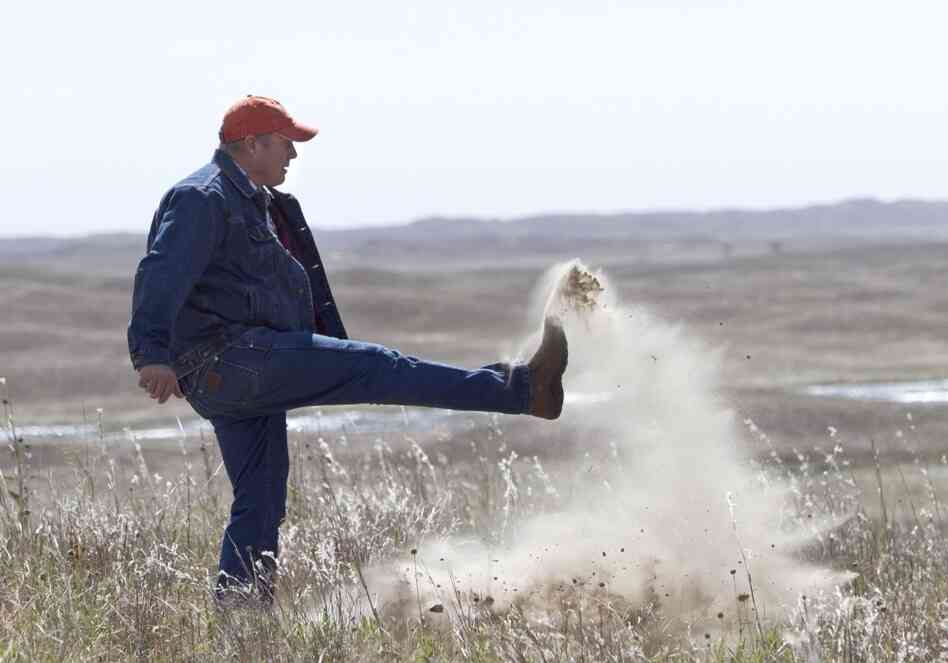 Atkinson, Neb., rancher Bruce Boettcher, who opposes the Keystone XL pipeline, kicks up sand on his land, to demonstrate the fragility of the sandhills near the planned route of the pipeline.