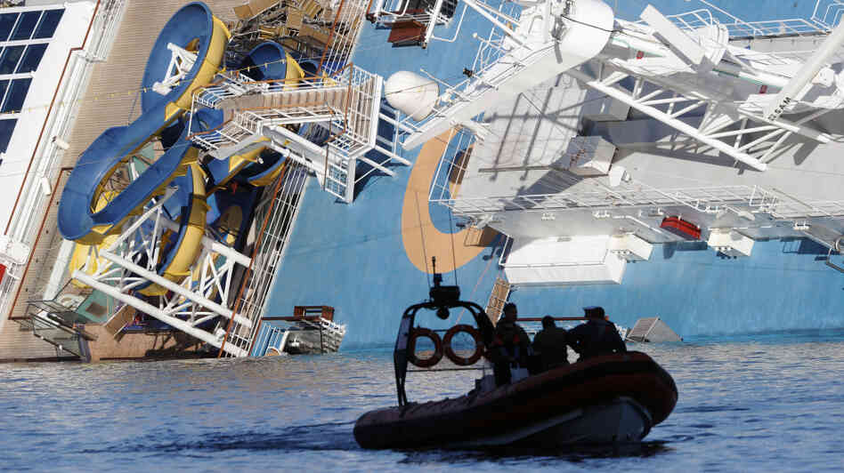 A coast guard boat passes the Costa Concordia, as the cruise liner lies aground in front of the harbor of Giglio Island.
