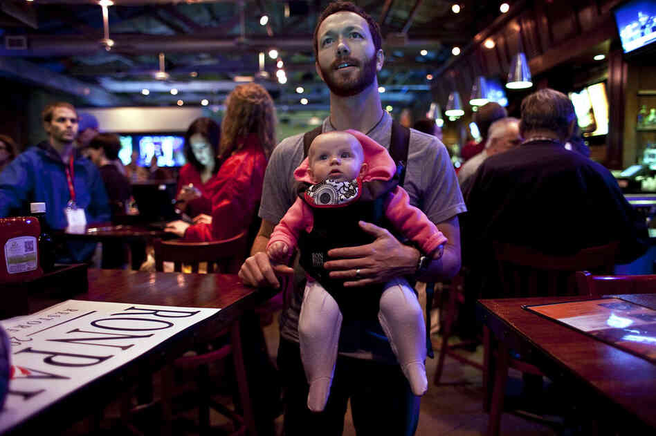 Kenny Ball holds his daughter, McKenna, while watching primary returns at Ron Paul's primary night campaign rally in Columbia. 
