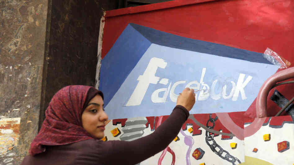 A student paints the Facebook logo on a mural commemorating Egypt's revolution last spring. The team from the CIA's Open Source Center monitors social media activity overseas.