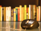 A computer mouse in front of a shelf of books. A computer mouse in front of a shelf of books.