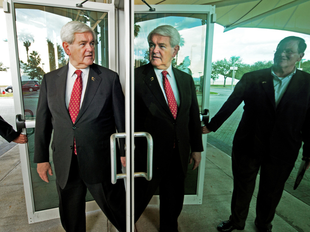 Newt Gingrich is refuting new attacks about his role at mortgage giant Freddie Mac. Gingrich's reflection is seen here as he walks out mirrored doors in Tampa, Fla. to deliver remarks and greet supporters on Jan. 23.
