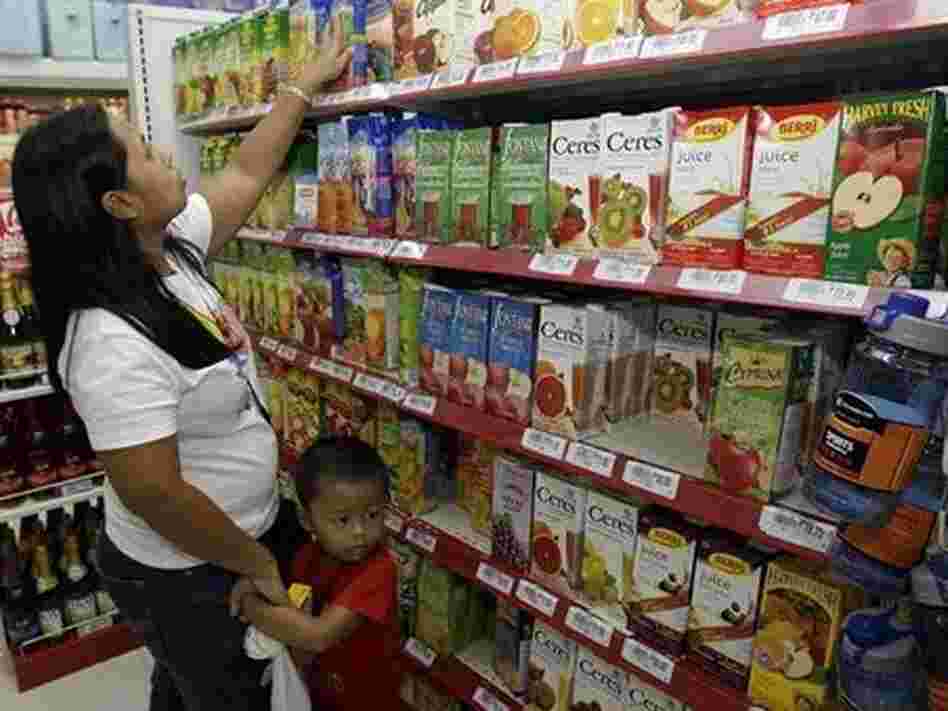 A woman with her son checks labels on fruit drinks in a store in Manila, Philippines. A woman with her son checks labels on fruit drinks in a store in Manila, Philippines.