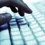 A hand on a computer keyboard. A hand on a computer keyboard.