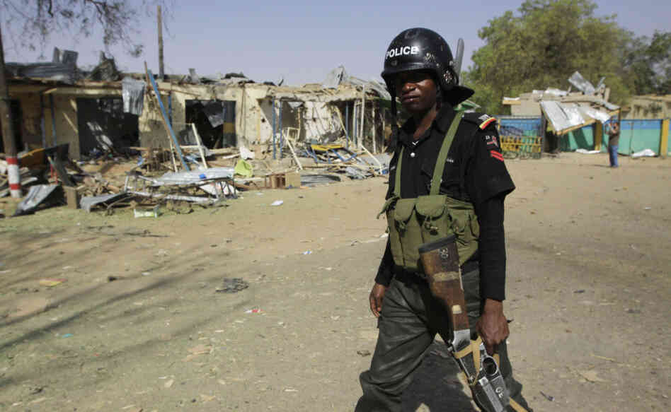 A police officer walks past the ruins of a market outside the state police headquarters in Kano, Nigeria, on Tuesday. A police officer walks past the ruins of a market outside the state police headquarters in Kano, Nigeria, on Tuesday.