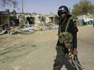A police officer walks past the ruins of a market outside the state police headquarters in Kano, Nigeria, on Tuesday. A police officer walks past the ruins of a market outside the state police headquarters in Kano, Nigeria, on Tuesday.