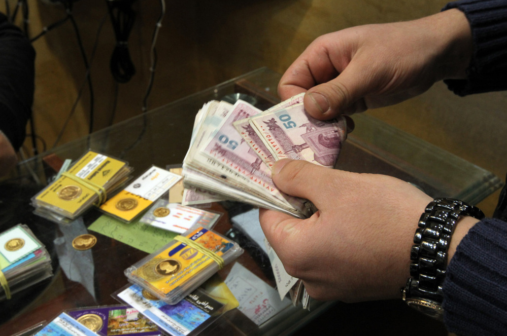 An Iranian man counts banknotes after exchanging a gold coin for cash in Tehran on Monday. Gold coins were being exchanged for over 10 million rials as the Iranian currency continues to lose value against the U.S. dollar.