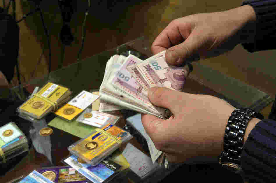 An Iranian man counts banknotes after exchanging a gold coin for cash in Tehran on Monday. Gold coins were being exchanged for over 10 million rials as the Iranian currency continues to lose value against the U.S. dollar.