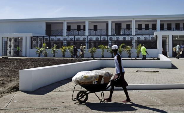A worker pushes a wheelbarrow past the new National Teaching Hospital in Mirebalais, Haiti, on Jan. 10. When it opens this summer, the 320-bed facility will be Haiti's largest hospital and provide services and a level of care well beyond what's currently available.
