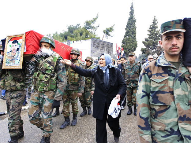A woman throws rice as a Syrian soldier carries the coffin of a comrade during a funeral at the military hospital in Homs, Syria, this week. The soldiers were killed by gunmen, a Syrian government official said. 