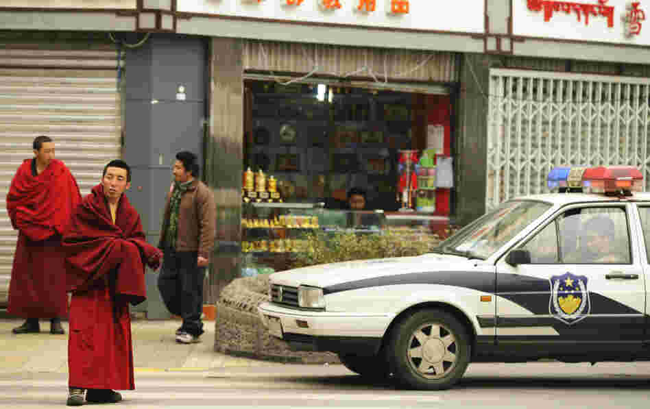 Ethnic Tibetan monks (left) walk past police vehicles on a street in Chengdu in China's Sichuan province Thursday. The Tibetan-inhabited region of West Sichuan appeared to be under lockdown after recent clashes.