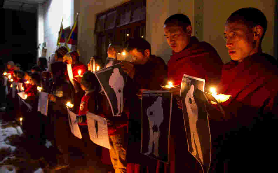 During a candlelight vigil in Dharamsala, India, on Wednesday, Tibetan Buddhist monks hold pictures of Tibetans they say were shot by Chinese security forces earlier this week. 