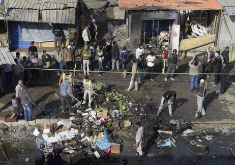 People gather at the scene of a car bomb attack in Zafaraniyah, Baghdad, Iraq on Friday. A suicide bomber detonated an explosives-packed car near a funeral procession killing and injuring dozens of Iraqis, police said. People gather at the scene of a car bomb attack in Zafaraniyah, Baghdad, Iraq on Friday. A suicide bomber detonated an explosives-packed car near a funeral procession killing and injuring dozens of Iraqis, police said.