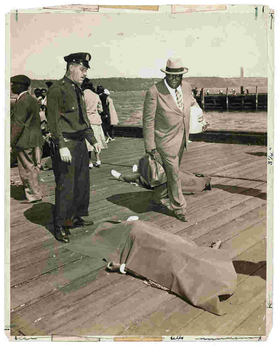 [Police officer and lodge member looking at blanket-covered body of woman trampled to death in excursion-ship stampede, New York], Aug. 18, 1941