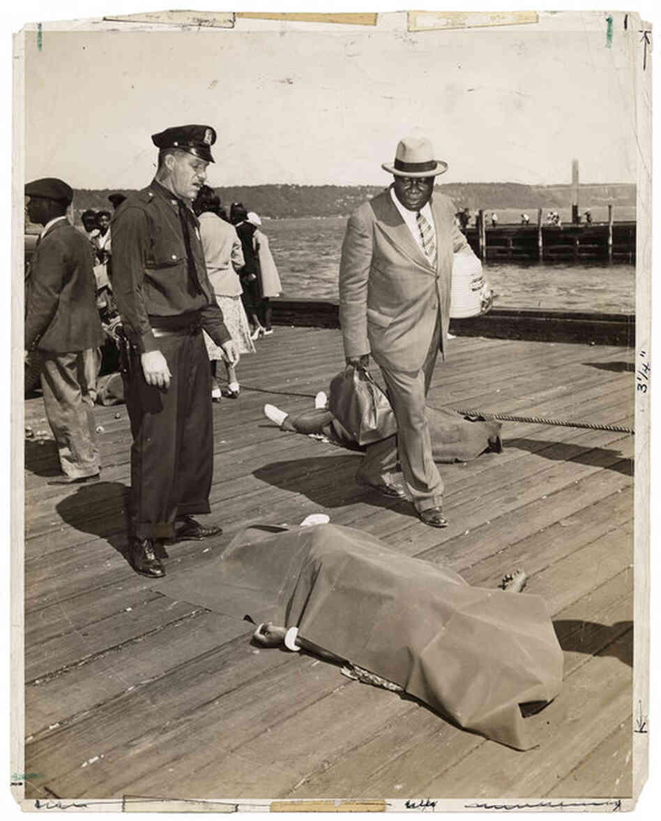 [Police officer and lodge member looking at blanket-covered body of woman trampled to death in excursion-ship stampede, New York], Aug. 18, 1941